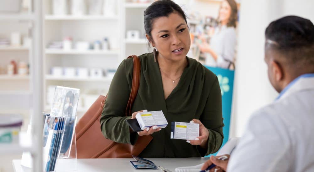 Femme comptoir pharmacie tenant boîtes de médicaments Remboursement générique